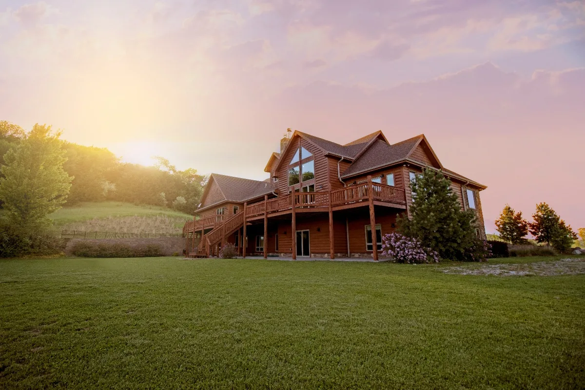 Casa de madera con jardín y terraza al atardecer.
