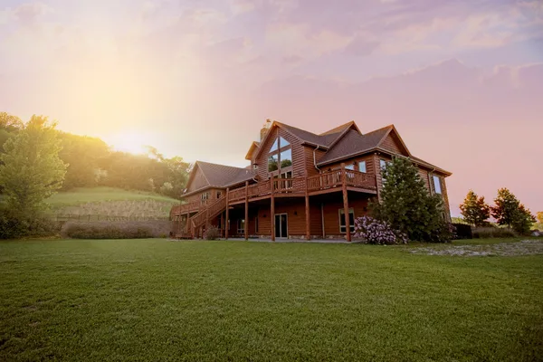 Casa de madera con jardín y terraza al atardecer.